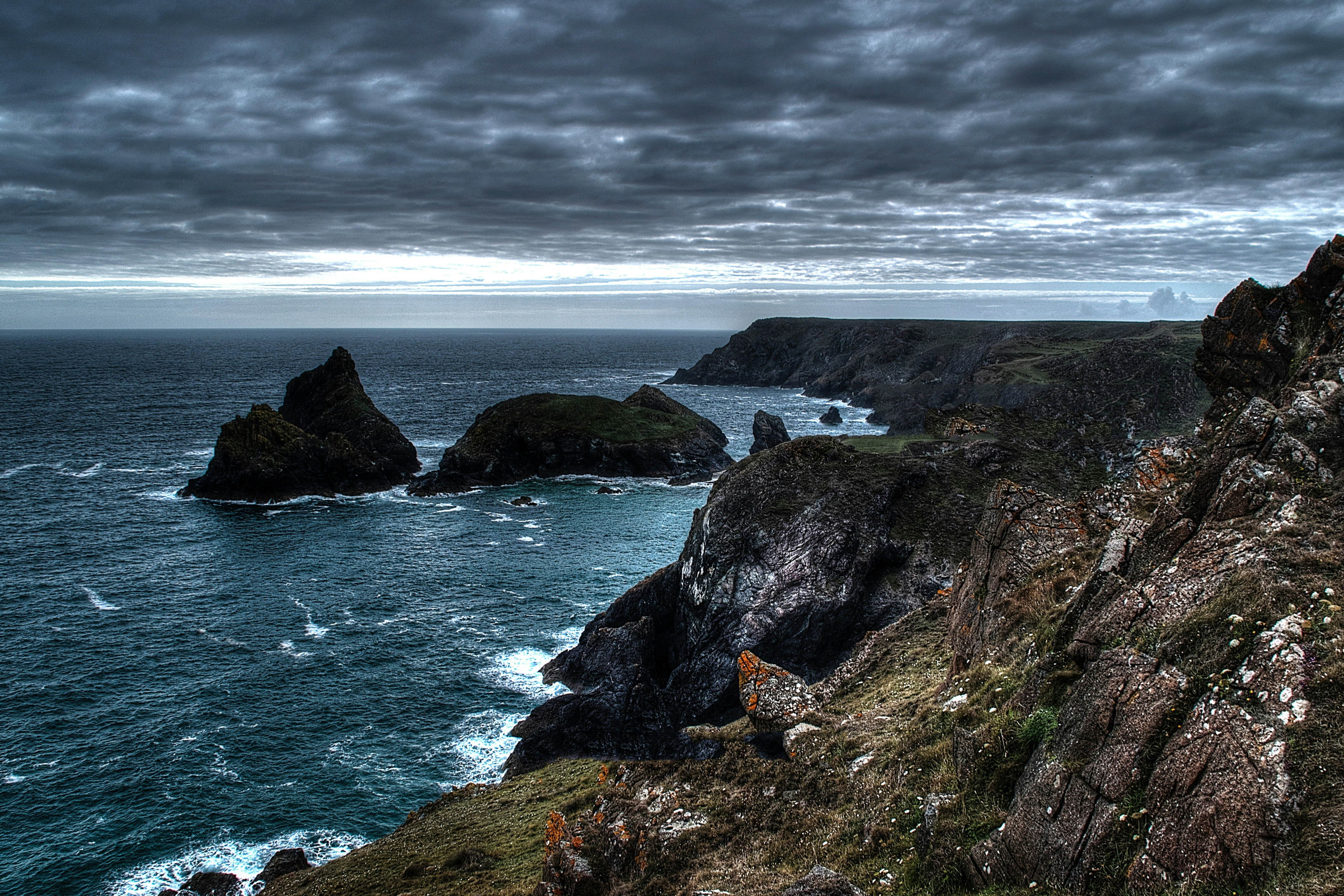 cliff beside body of water during cloudy day